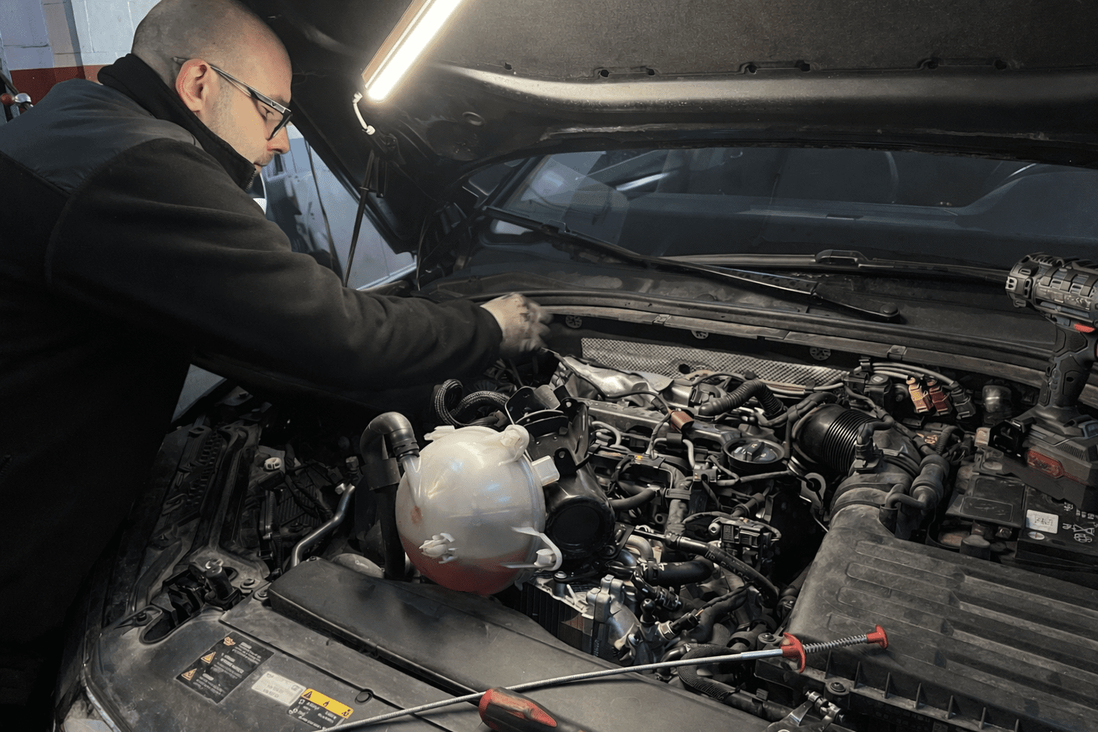 Focused mechanic working on motorcycle repair in a garage setting.