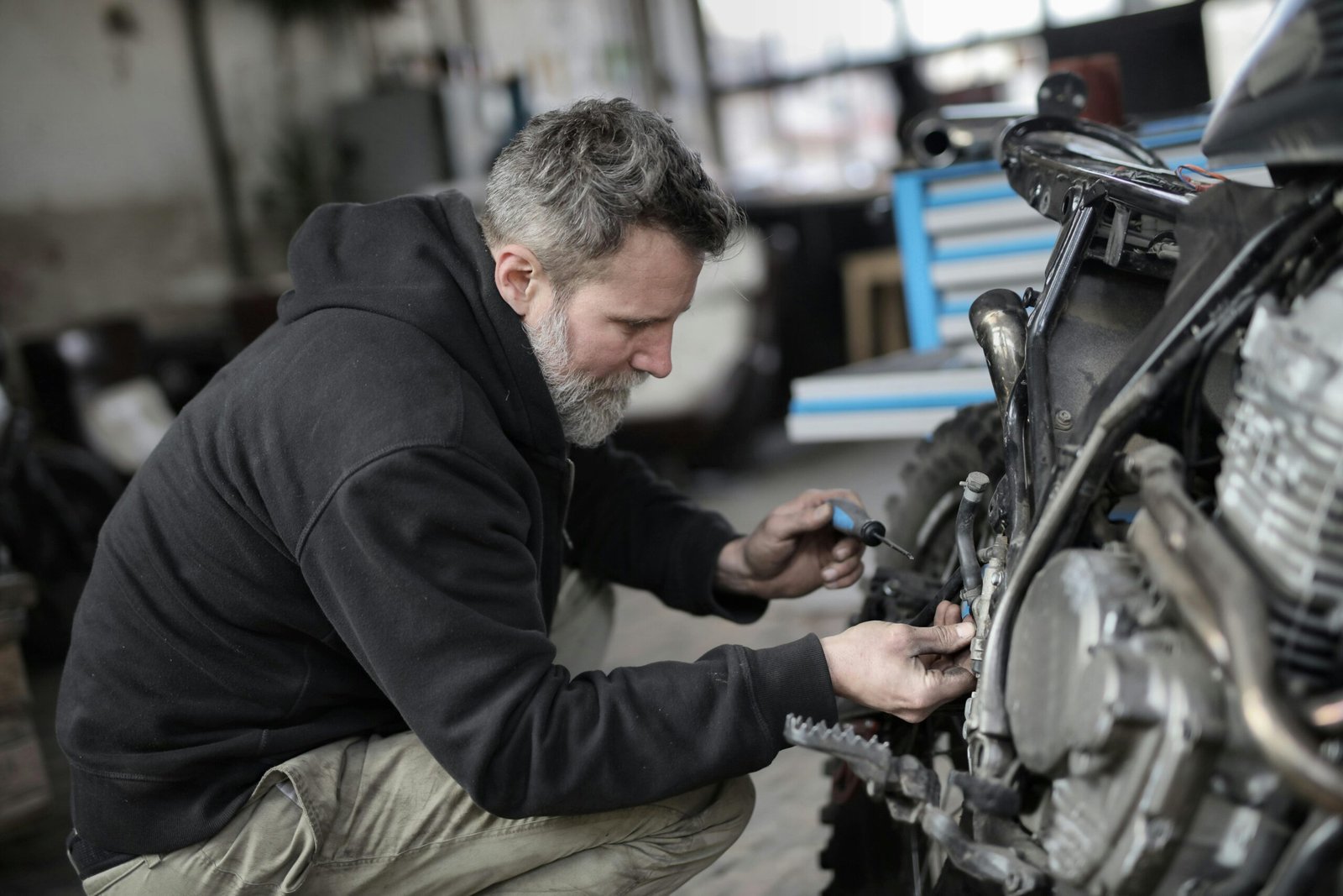 Focused mechanic working on motorcycle repair in a garage setting.